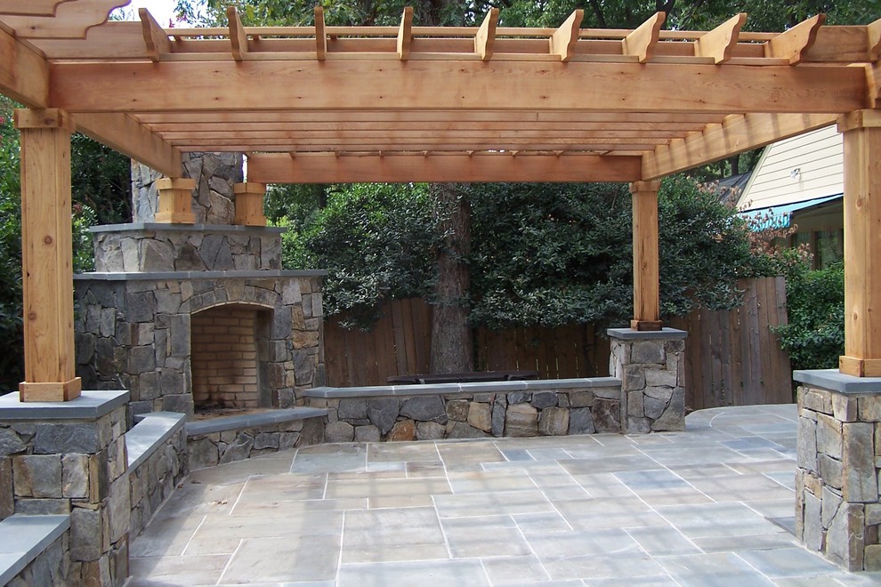 This is an example of a medium sized traditional back patio in DC Metro with natural stone paving and a pergola.