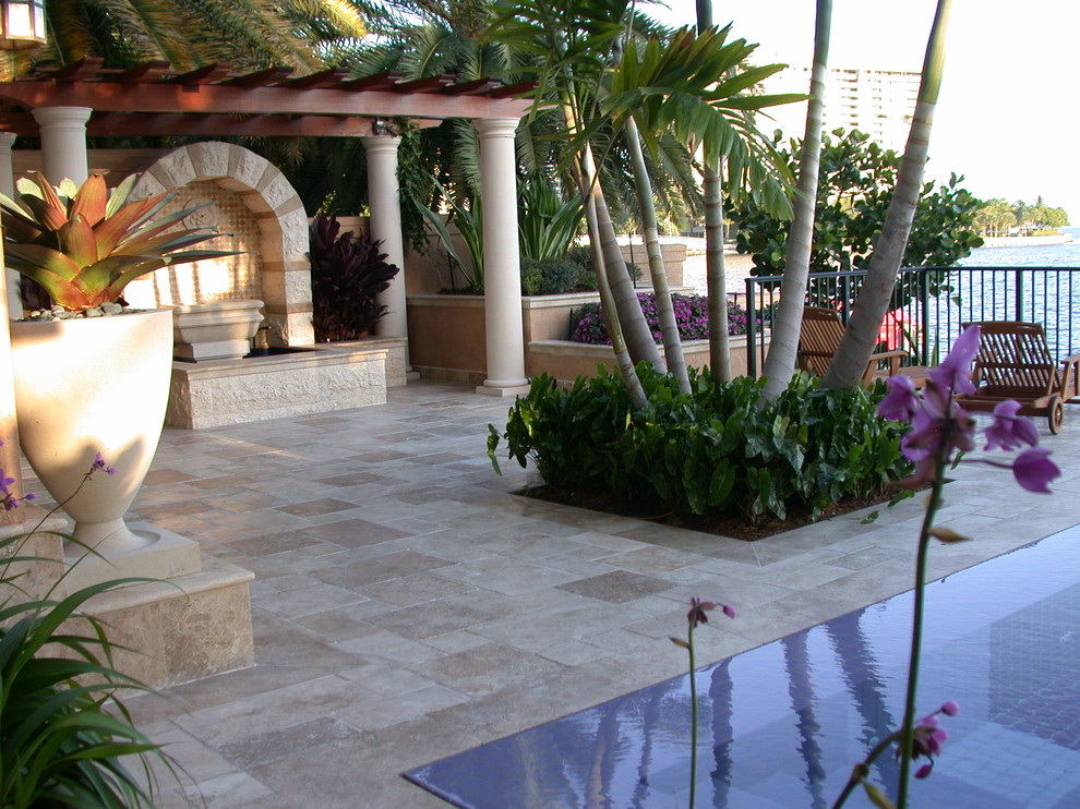 Patio fountain - mid-sized modern courtyard stone patio fountain idea in Miami with a pergola