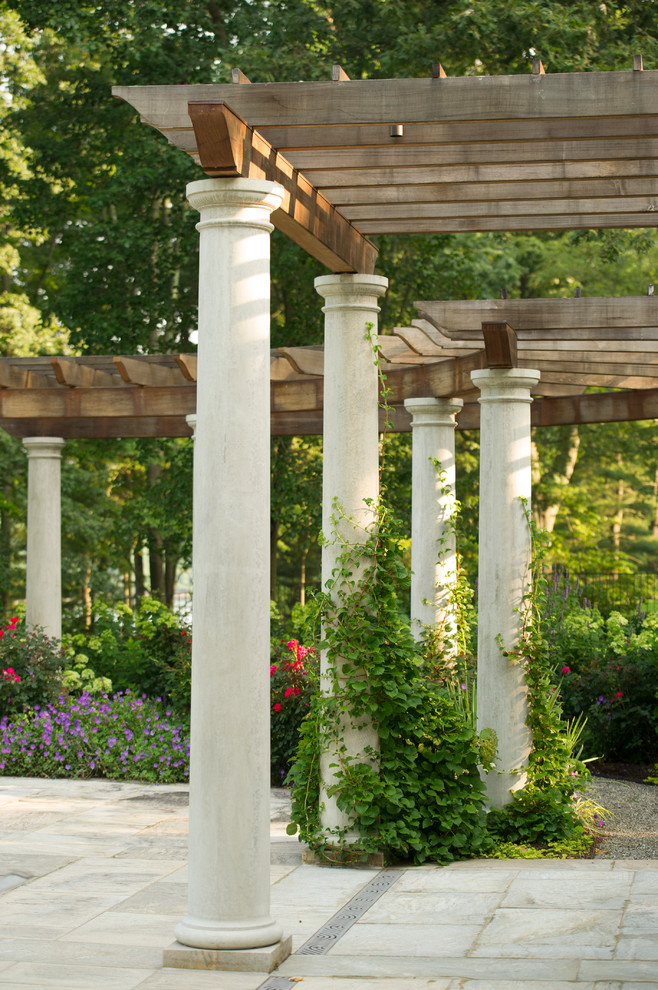 Inspiration pour une terrasse arrière traditionnelle de taille moyenne avec des pavés en pierre naturelle et une pergola.
