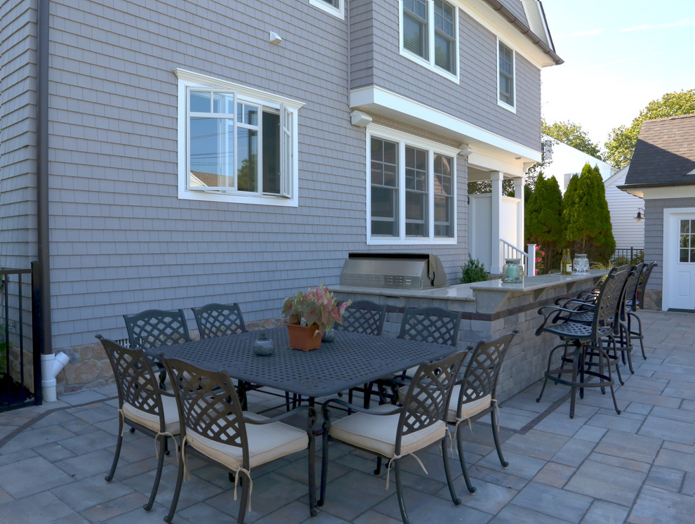 Modelo de patio clásico de tamaño medio sin cubierta en patio trasero con cocina exterior y adoquines de hormigón