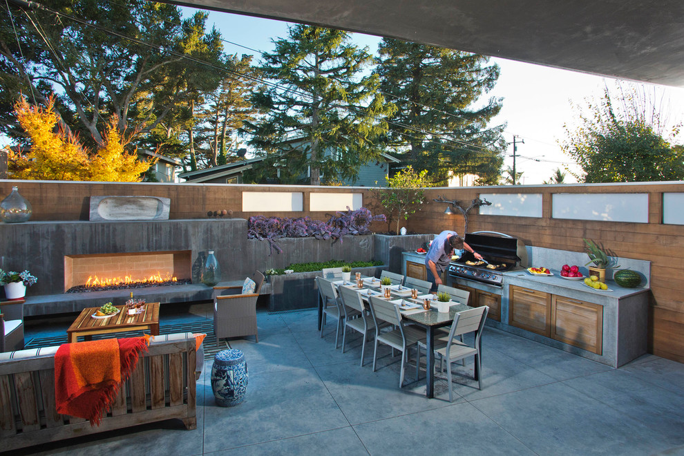 На фото: большой двор на заднем дворе в стиле модернизм с летней кухней и покрытием из декоративного бетона без защиты от солнца