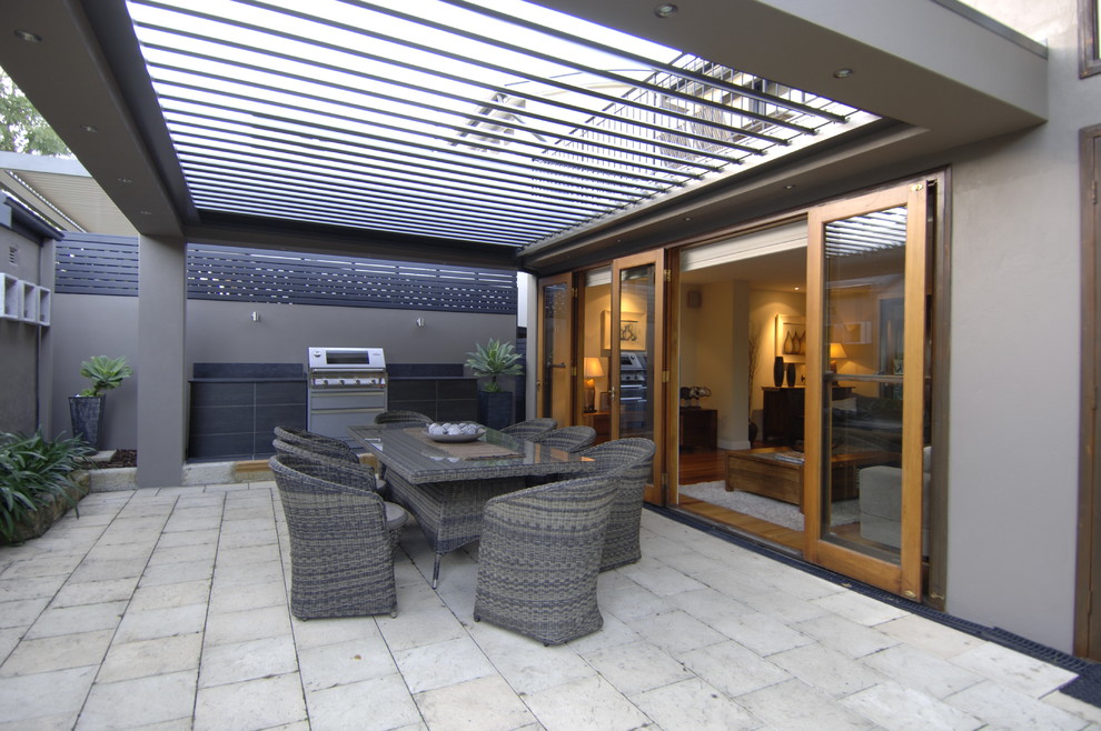 Medium sized contemporary back patio in Sydney with natural stone paving and a pergola.
