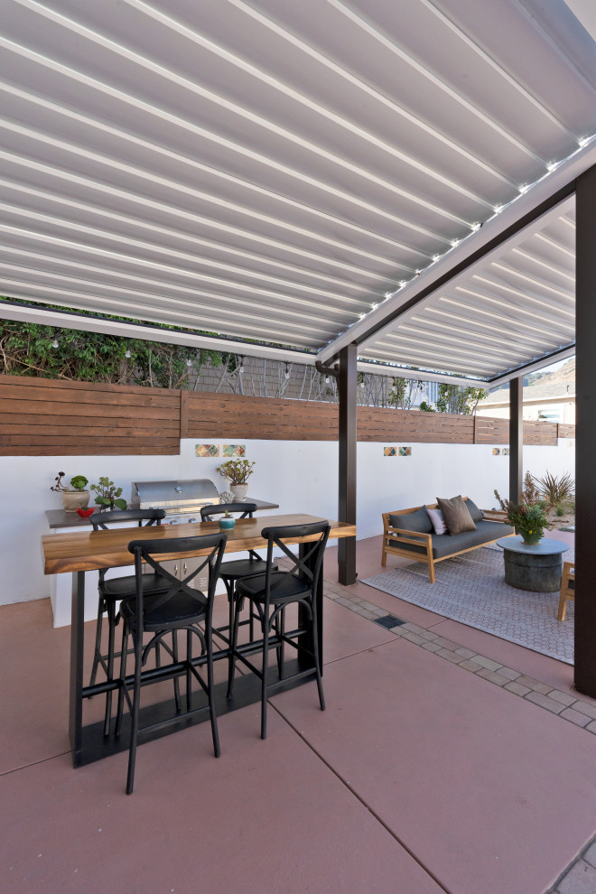 Immagine di un patio o portico mediterraneo di medie dimensioni e dietro casa con lastre di cemento e una pergola