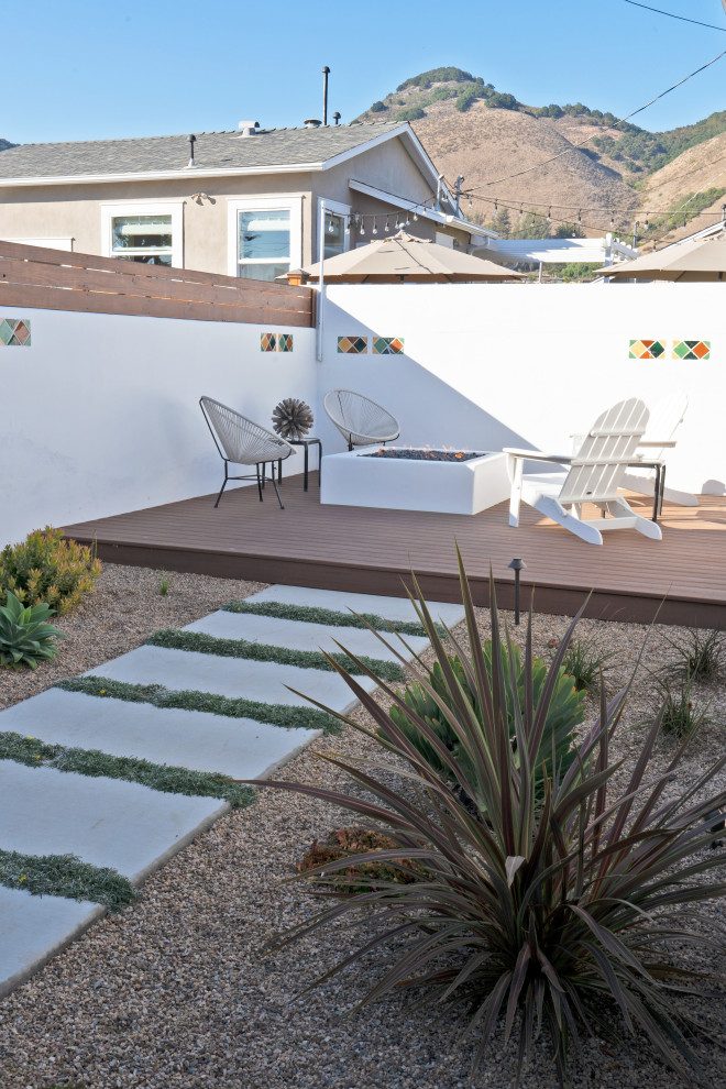 This is an example of a medium sized mediterranean back patio in San Luis Obispo with a fire feature, concrete slabs and a pergola.