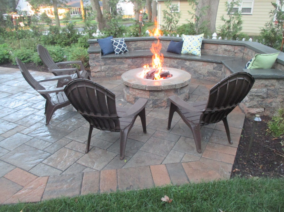 Photo of a large classic back patio in New York with a fire feature, natural stone paving and no cover.
