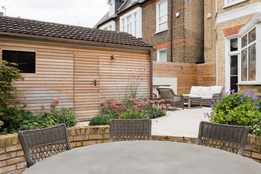 This is an example of a medium sized contemporary back patio in London with natural stone paving and a fireplace.