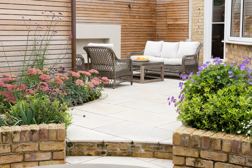 Foto di un patio o portico design di medie dimensioni e dietro casa con pavimentazioni in pietra naturale e un caminetto
