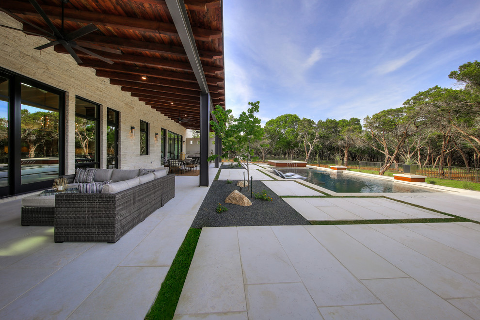 Immagine di un grande patio o portico chic dietro casa con pavimentazioni in pietra naturale e un tetto a sbalzo