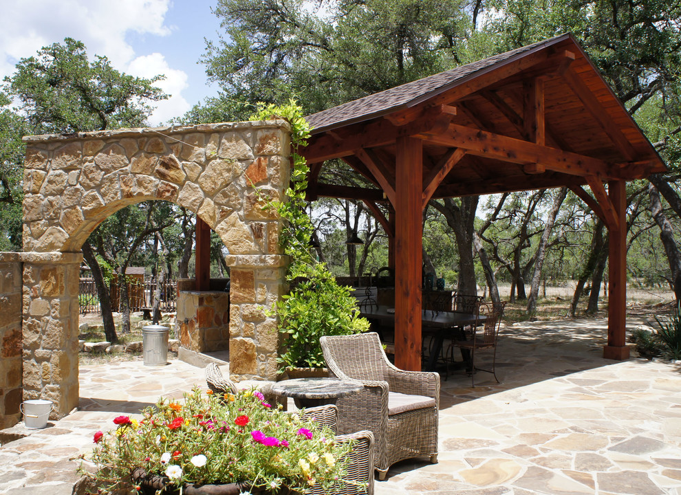 Foto di un grande patio o portico stile americano dietro casa con pavimentazioni in pietra naturale e un gazebo o capanno