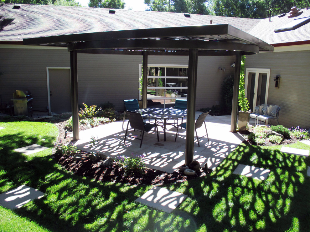 Esempio di un patio o portico design di medie dimensioni e dietro casa con pavimentazioni in cemento e una pergola