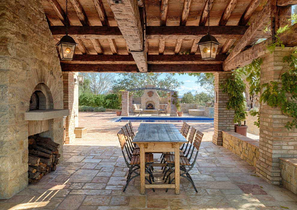 Esempio di un grande patio o portico mediterraneo nel cortile laterale con pavimentazioni in pietra naturale e un tetto a sbalzo