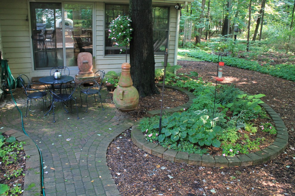 Example of a mid-sized mountain style courtyard concrete paver patio fountain design in Grand Rapids with no cover