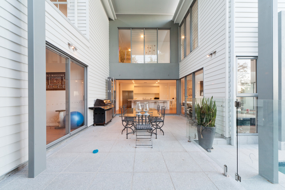 Идея дизайна: двор среднего размера на внутреннем дворе в современном стиле с мощением тротуарной плиткой, навесом и зоной барбекю