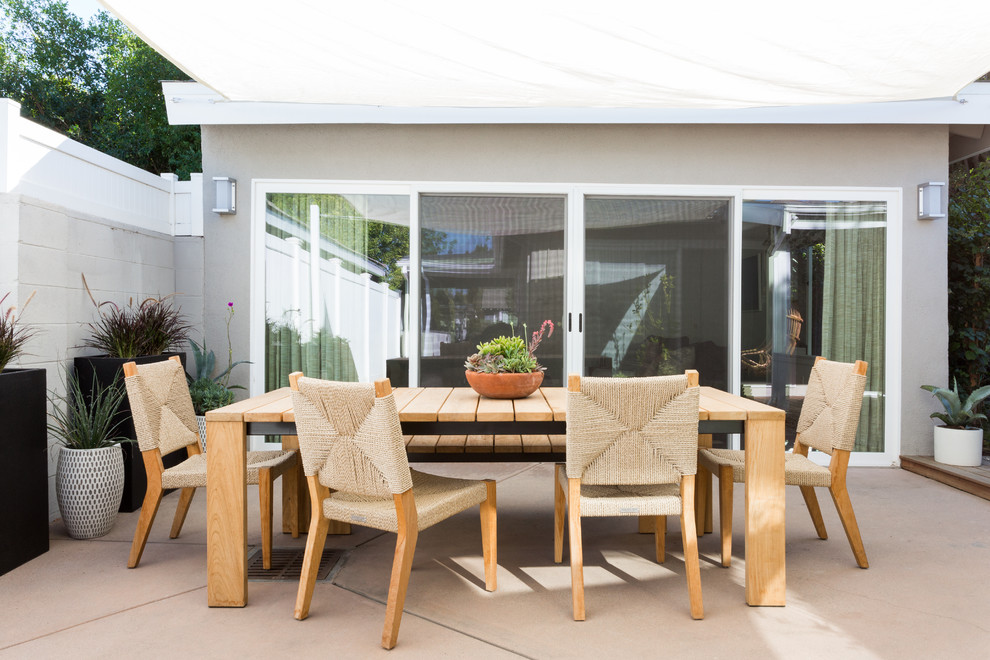 Cette image montre une terrasse arrière vintage de taille moyenne avec une dalle de béton et un auvent.