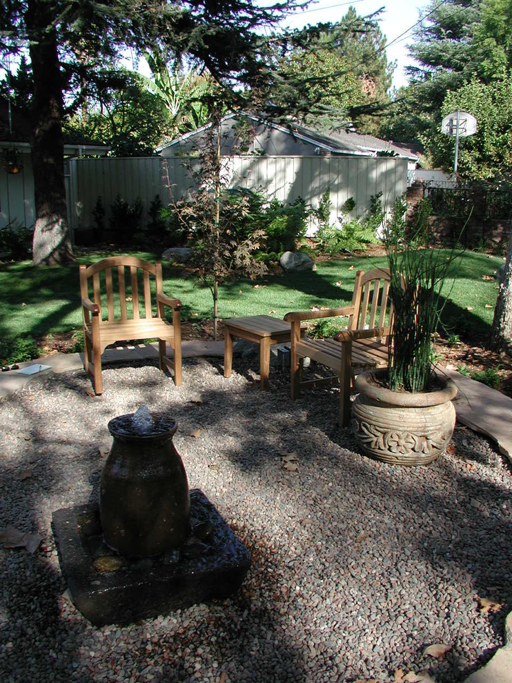 Ejemplo de patio actual de tamaño medio sin cubierta en patio trasero con gravilla y fuente