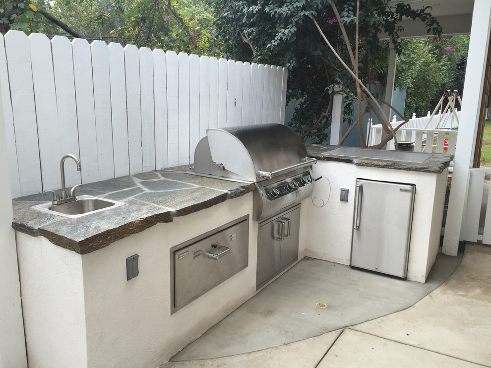 Example of a mid-sized classic backyard stone patio kitchen design in Los Angeles with a pergola
