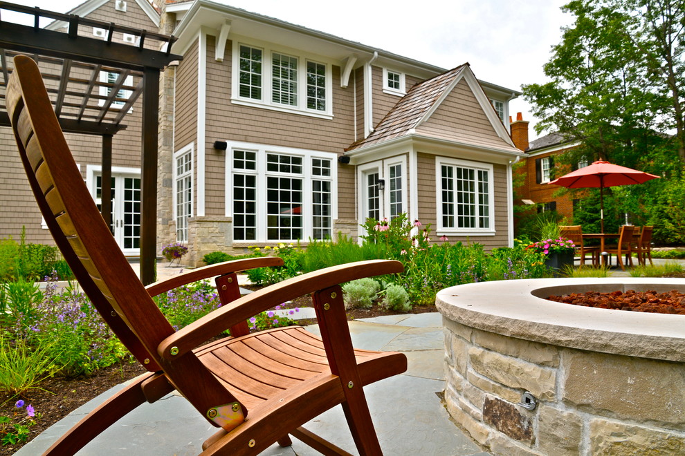 Immagine di un patio o portico vittoriano dietro casa con un focolare, una pergola e pavimentazioni in pietra naturale