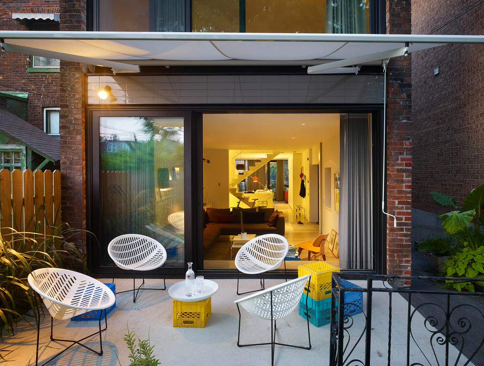 Idee per un piccolo patio o portico contemporaneo dietro casa con lastre di cemento e un parasole