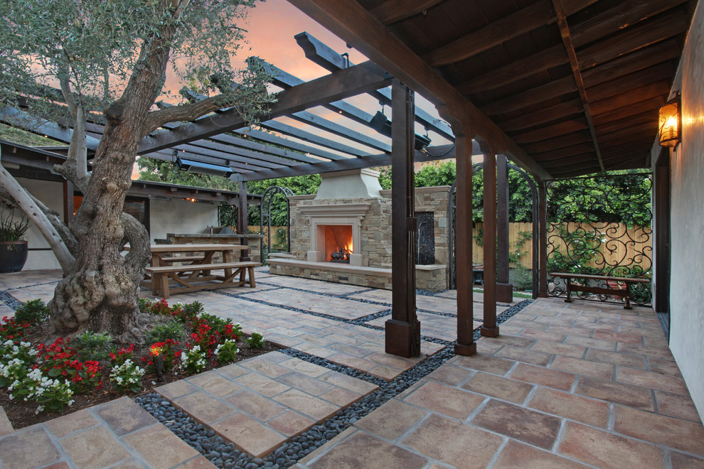 Idée de décoration pour une terrasse méditerranéenne de taille moyenne avec un foyer extérieur, une cour, des pavés en pierre naturelle et un gazebo ou pavillon.