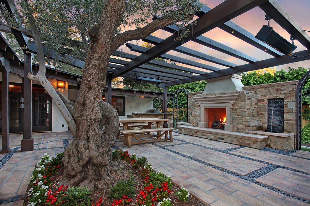 Réalisation d'une terrasse méditerranéenne de taille moyenne avec un foyer extérieur, une cour, des pavés en pierre naturelle et un gazebo ou pavillon.