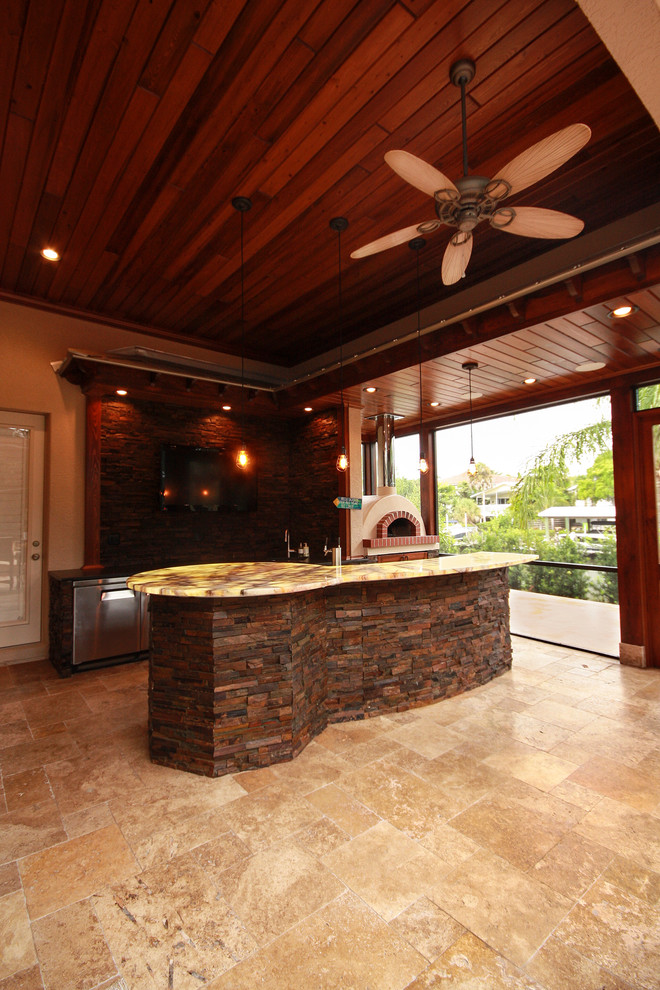 Cette photo montre une très grande terrasse arrière chic avec une cuisine d'été, des pavés en pierre naturelle et une extension de toiture.