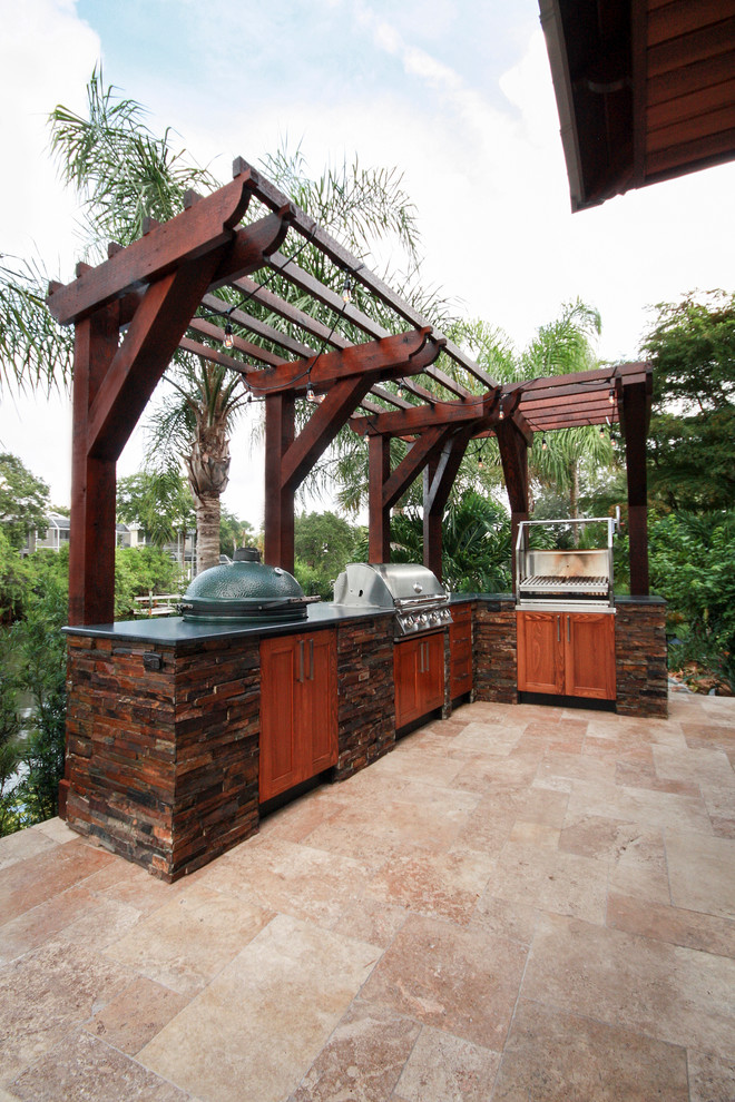 Cette photo montre une très grande terrasse arrière exotique avec une cuisine d'été, des pavés en pierre naturelle et une pergola.