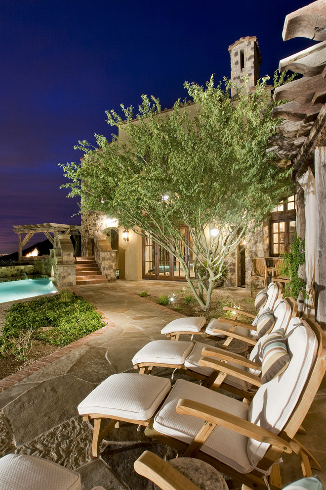 Example of a tuscan stone patio design in Phoenix with no cover