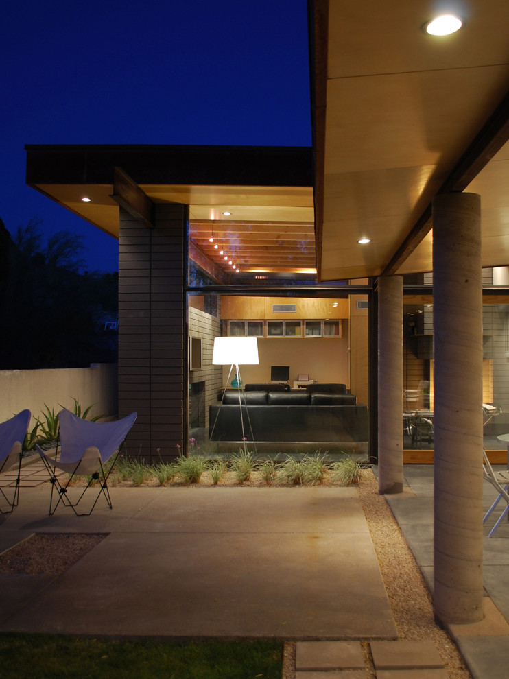 This is an example of a small modern back patio in Phoenix with concrete slabs and a roof extension.