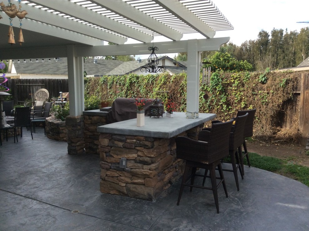 Inspiration pour une grande terrasse arrière chalet avec une cuisine d'été, une dalle de béton et un gazebo ou pavillon.