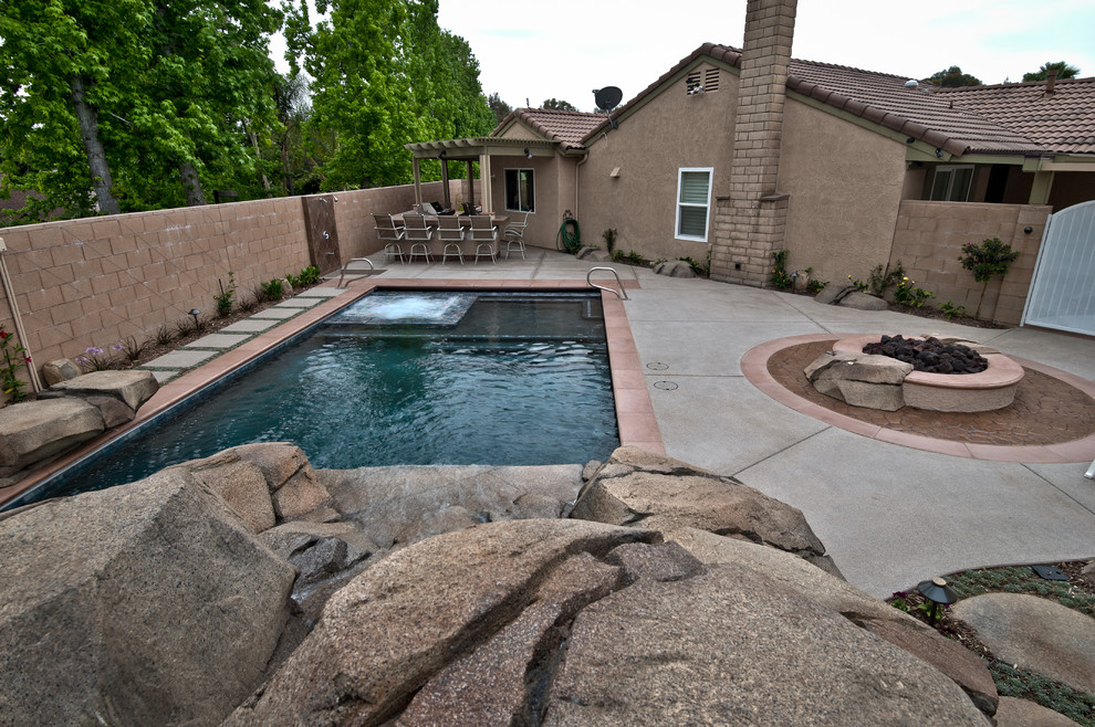 Foto di un patio o portico tropicale di medie dimensioni e dietro casa con un focolare, lastre di cemento e una pergola