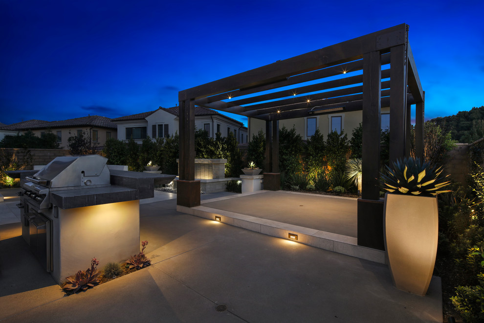Photo of a medium sized contemporary back patio in Orange County with a water feature, natural stone paving and a pergola.