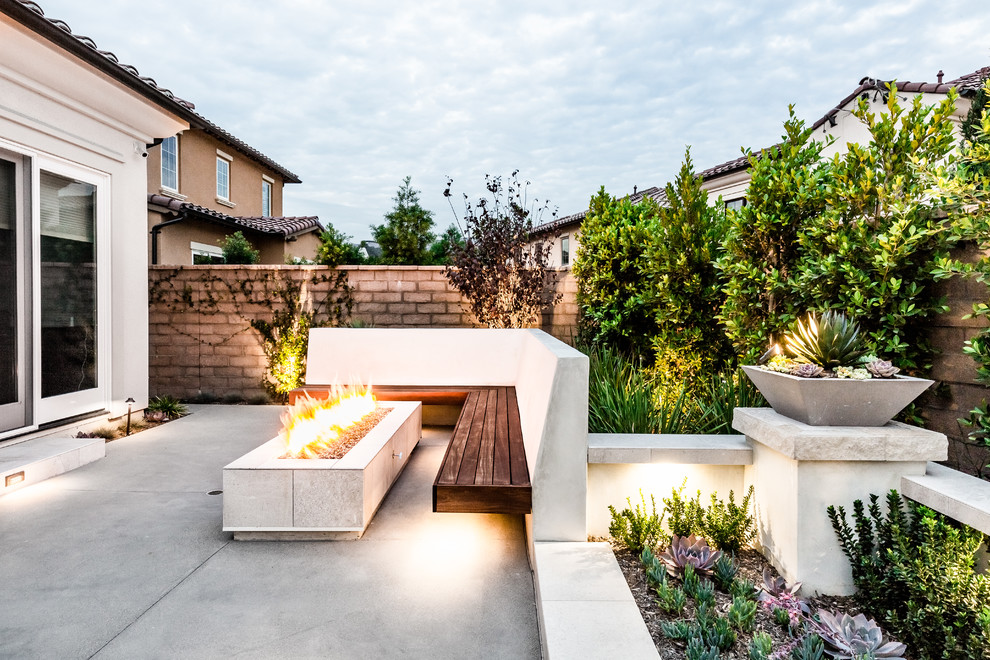 Contemporary back patio in Orange County with a fire feature and no cover.
