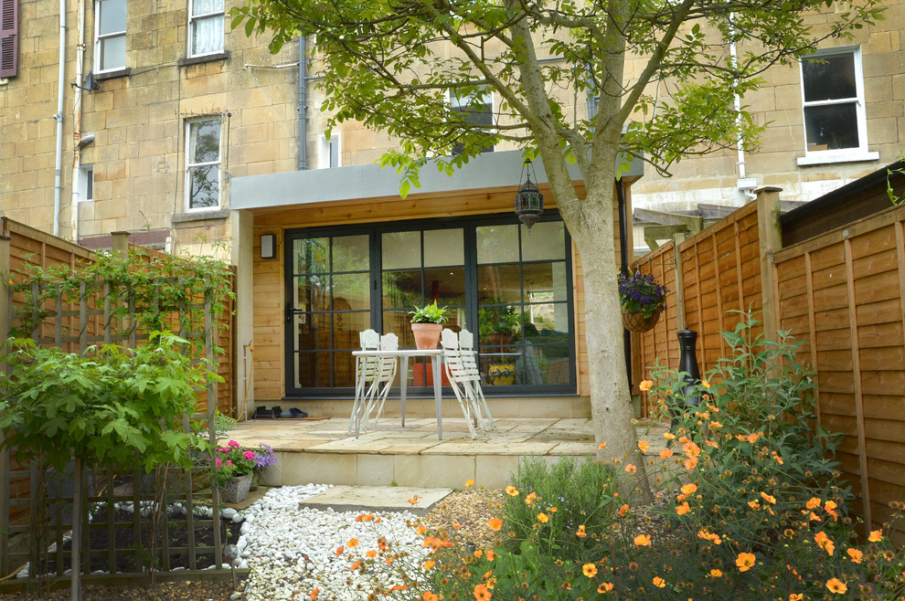 Ejemplo de patio actual pequeño en patio trasero y anexo de casas con jardín de macetas y adoquines de piedra natural