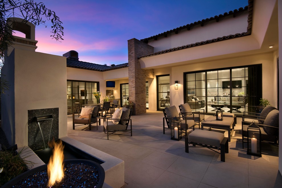 This is an example of a large contemporary back patio in Phoenix with a fire feature, tiled flooring and no cover.
