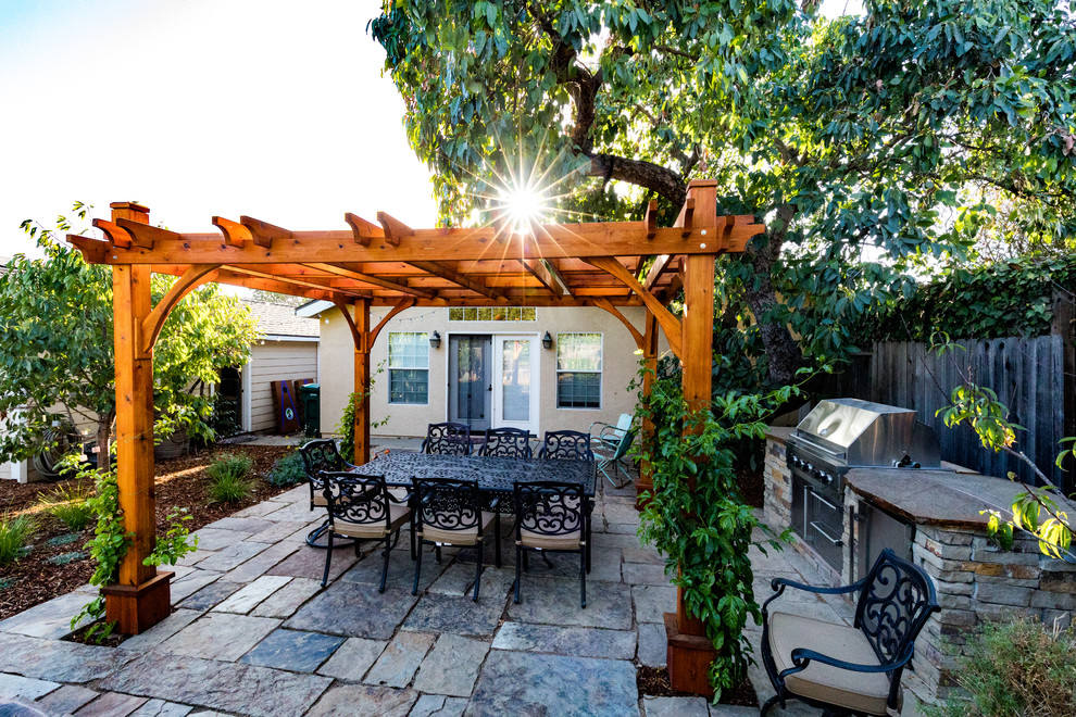 Tuscan backyard stone patio kitchen photo in San Luis Obispo with a pergola