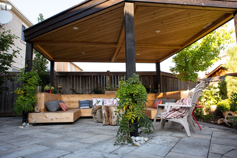 Modelo de patio de estilo americano de tamaño medio en patio trasero con adoquines de hormigón y cenador