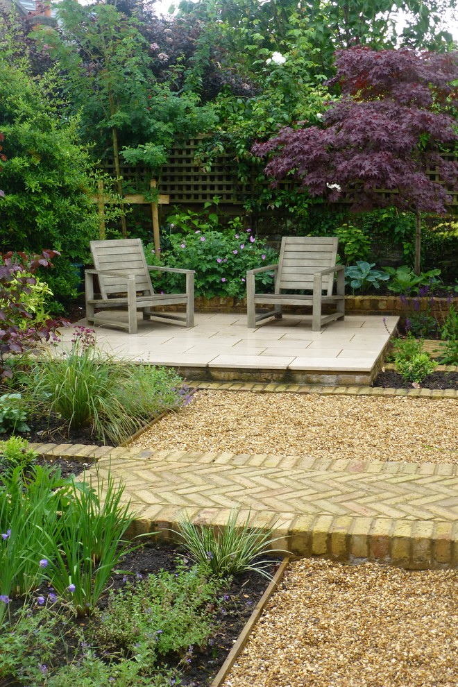 This is an example of a small classic back patio in London with natural stone paving.