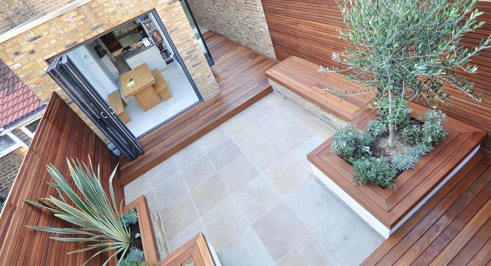 Mediterranean back patio in London with natural stone paving.