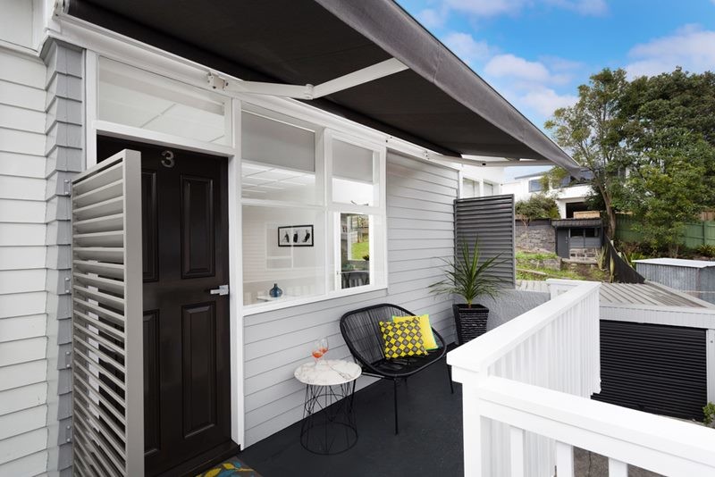 Small modern front patio in Auckland with concrete slabs and an awning.
