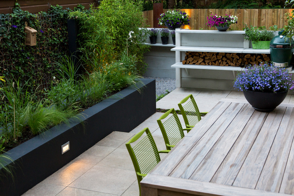 Photo of a small contemporary back patio in Amsterdam with an outdoor kitchen, tiled flooring and no cover.