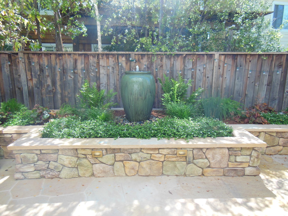 Esempio di un piccolo patio o portico chic dietro casa con fontane, pavimentazioni in pietra naturale e una pergola
