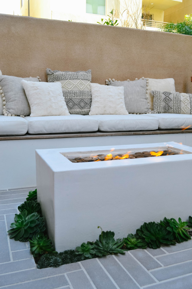 Photo of a small contemporary courtyard patio in Orange County with a fire feature and concrete paving.