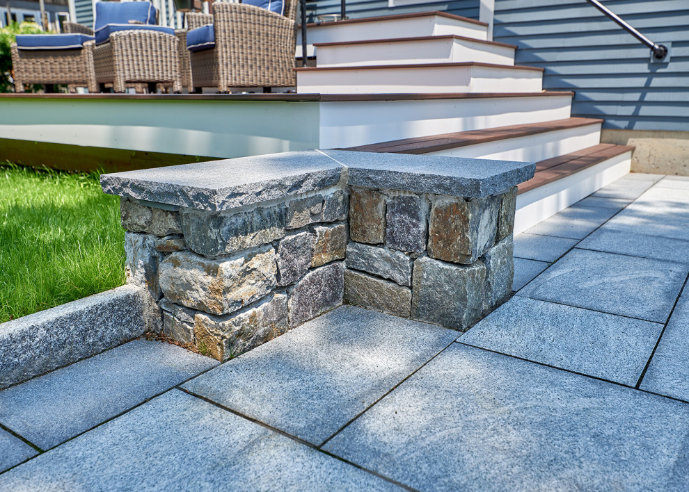 This is an example of a small traditional back patio in Boston with a fire feature, natural stone paving and no cover.