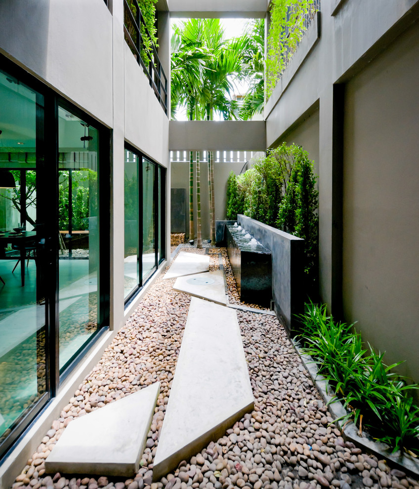 Idee per un piccolo patio o portico contemporaneo nel cortile laterale con fontane, cemento stampato e un tetto a sbalzo