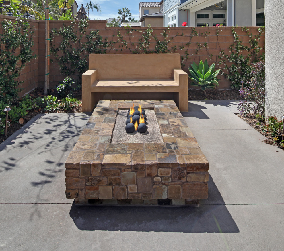 Photo of a medium sized classic back patio in Orange County with a fire feature and concrete slabs.