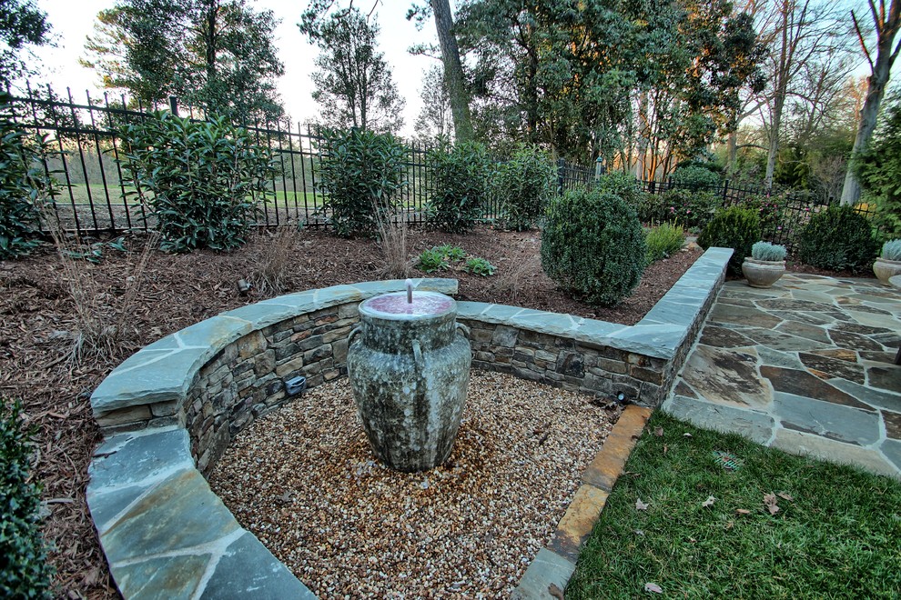 Aménagement d'une terrasse arrière classique de taille moyenne avec un point d'eau et des pavés en pierre naturelle.