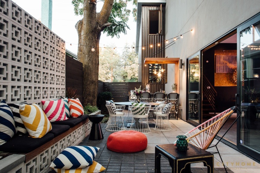 Foto di un patio o portico eclettico di medie dimensioni e dietro casa con pavimentazioni in mattoni e un parasole