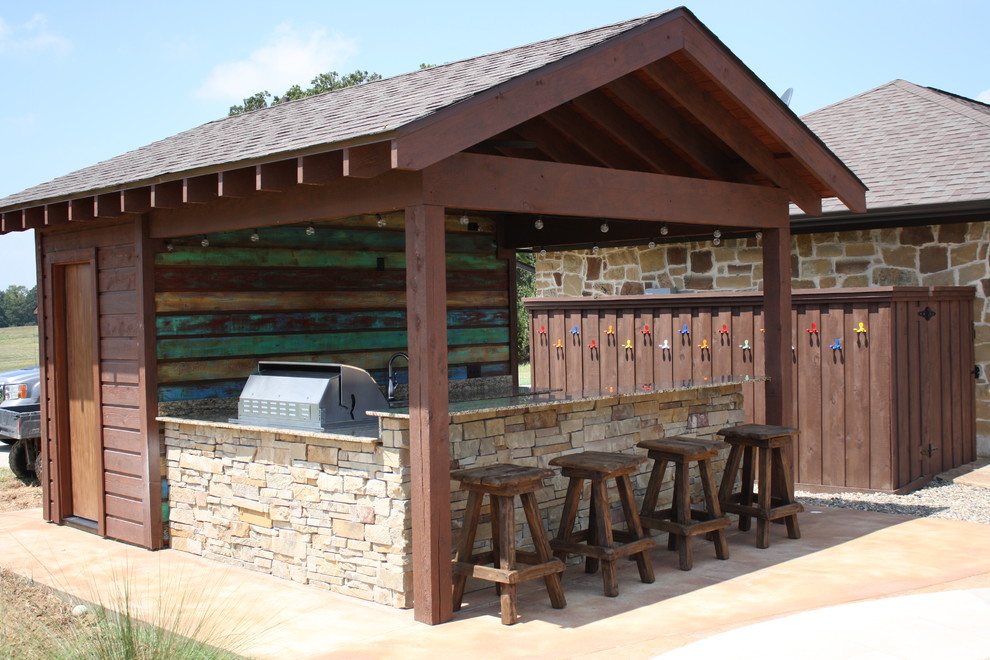 Réalisation d'une grande terrasse arrière chalet avec une cuisine d'été, des pavés en pierre naturelle et un gazebo ou pavillon.