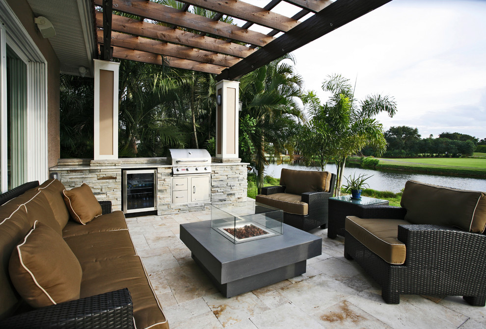Photo of a large classic back patio in Tampa with an outdoor kitchen, natural stone paving and a pergola.