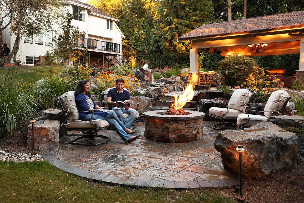 Large elegant backyard stone patio photo in Seattle with a gazebo and a fire pit